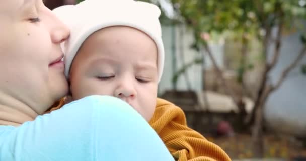 Famiglia felice insieme in una passeggiata all'aria aperta in una giornata estiva soleggiata. Una madre premurosa tiene il suo giovane figlio tra le braccia — Video Stock