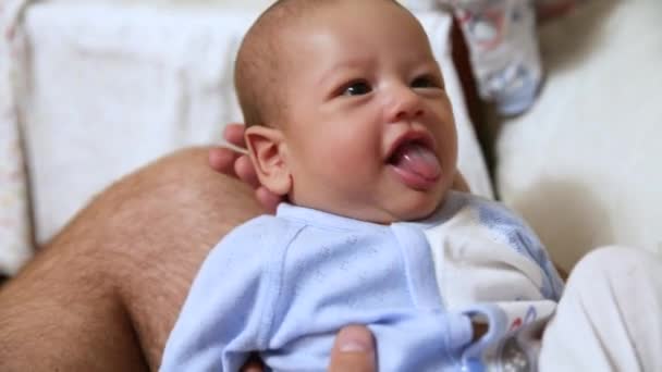 Een pasgeboren baby wordt wakker en opent zijn ogen. De vader houdt het kind overeind. Kinderopvang en ouderliefde concept — Stockvideo