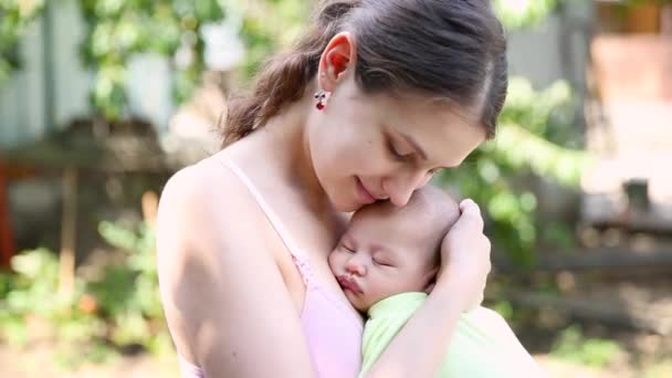 Little baby boy sleeping on moms chest outdoor. mother hugging sleeping baby in her arms and kissing the kid gently — Stock Video