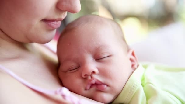 小男孩睡在妈妈的胸前。妈妈抱着熟睡的婴儿，轻轻地吻着孩子 — 图库视频影像