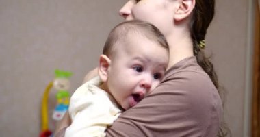 Annenin kollarındaki bebek kameraya bakıyor. Annelik kavramı