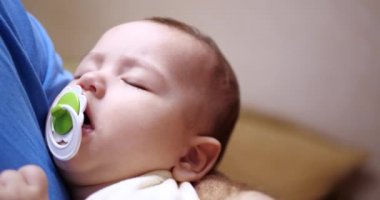 Küçük bir çocuk babasının kollarında uyuyakaldı. Baba bebeği uyutmak için sallıyor. Yakın plan. 4k