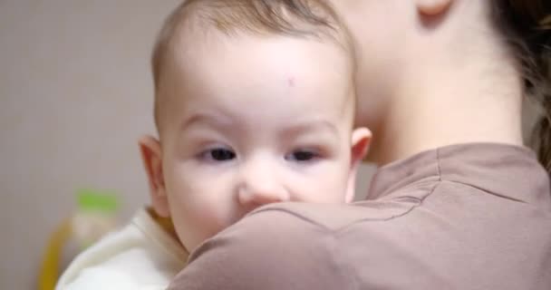Ребенок на маминых руках смотрит в камеру. Концепция материнства — стоковое видео