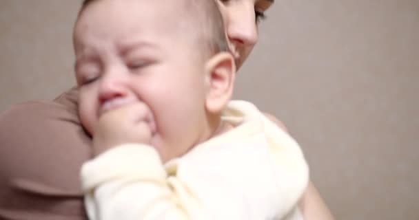 Mamma conforta e abbraccia un neonato che piange tra le braccia. bambino tra le braccia delle mamme guardando la macchina fotografica. Concetto di maternità — Video Stock