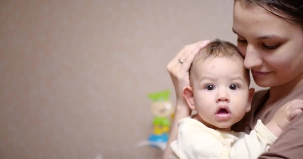 Ребенок на маминых руках смотрит в камеру. Концепция материнства — стоковое видео