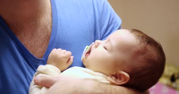 小さな子供が父親の腕の中で眠ってしまいました。パパは赤ん坊を寝かしつけてた。接近中だ。4k — ストック動画