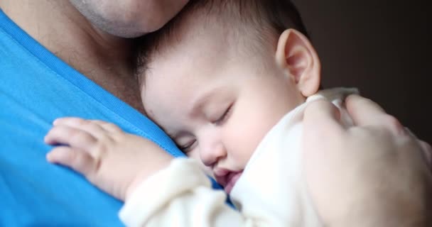 小さな子供が父親の腕の中で眠ってしまいました。パパは赤ん坊を寝かしつけてた。接近中だ。4k — ストック動画