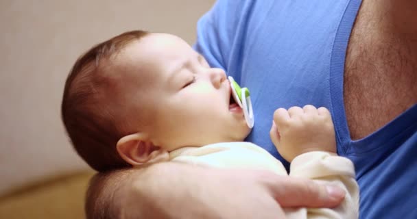 Ein kleines Kind schlief in den Armen seines Vaters ein. Papa wiegt das Baby in den Schlaf. Nahaufnahme. 4k — Stockvideo