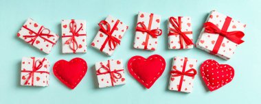Hediye kutularının ve renkli arka planda kırmızı tekstil kalplerinin üst görüntüsü. Kopya alanı ile Sevgililer Günü konsepti.