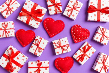 Beyaz hediye kutularının ve renkli arka planda kırmızı tekstil kalplerinin kompozisyonu. Sevgililer Günü konsepti.