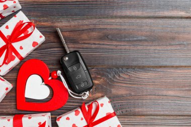 Tahta arka planda Sevgililer Günü hediyesinin üst görüntüsü. Araba anahtarı, hediye kutuları ve kopyalanmış bir kalp. Tatil için sürpriz konsept.