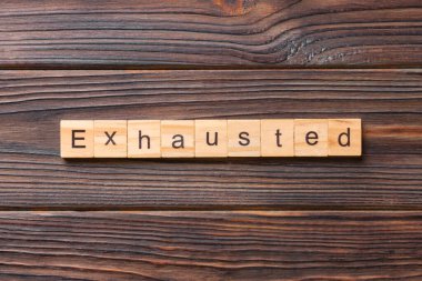 Tahta bloğa yazılmış tükenmiş bir kelime. Çimento masasında yorulmuş metin desing, konsept için.