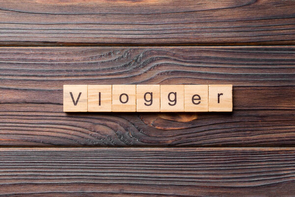 Vlogger word written on wood block. vlogger text on table, concept.