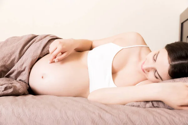 Έγκυος Γυναίκα Κάθεται Στο Κρεβάτι Και Αγγίζει Την Κοιλιά Της — Φωτογραφία Αρχείου
