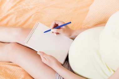 Hamile kadın not defterine not alır. Hamilelik kavramı Anne bebek bekliyor.