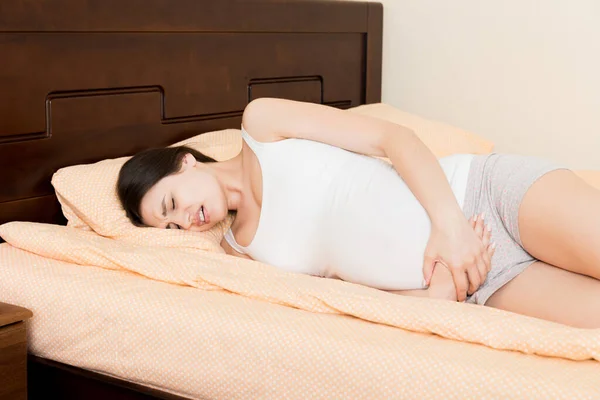 Junge Hübsche Schwangere Frau Sitzt Unter Schmerzen Auf Dem Bett — Stockfoto