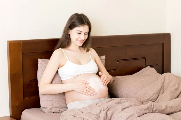 Gravid Flicka Sitter Hemma Sängen Och Smetar Stretch Märke Grädde — Stockfoto