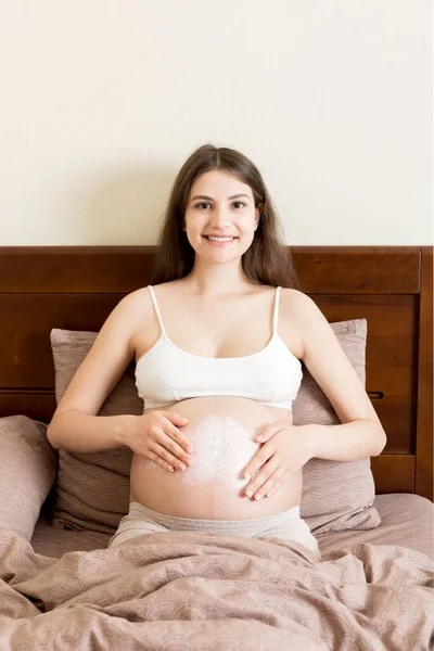 Uma Menina Grávida Senta Casa Cama Mancha Creme Marca Estiramento — Fotografia de Stock