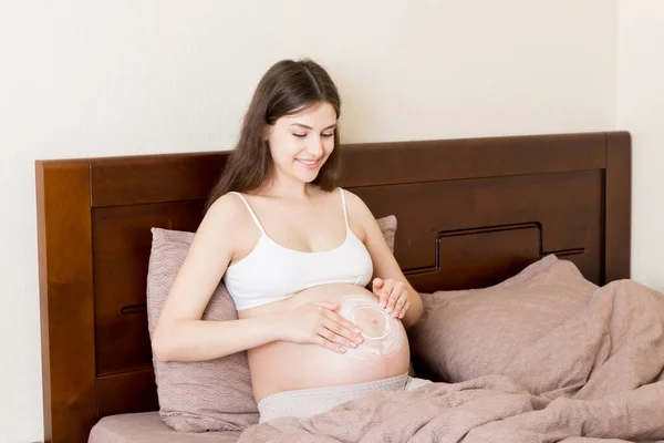 Gravid Flicka Sitter Hemma Sängen Och Smetar Stretch Märke Grädde — Stockfoto