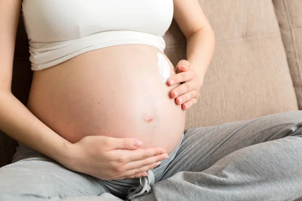 Těhotná Dívka Sedí Doma Posteli Rozmazává Břicho Krém Proti Striím — Stock fotografie