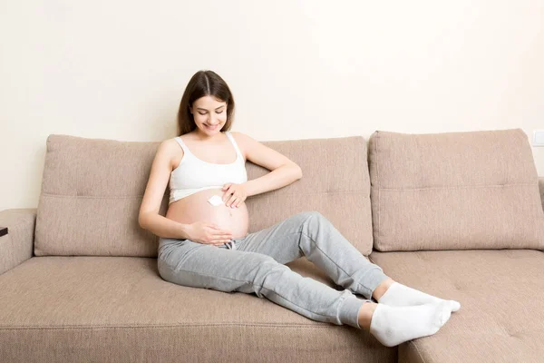 Una Chica Embarazada Sienta Casa Cama Unta Una Crema Estrías —  Fotos de Stock