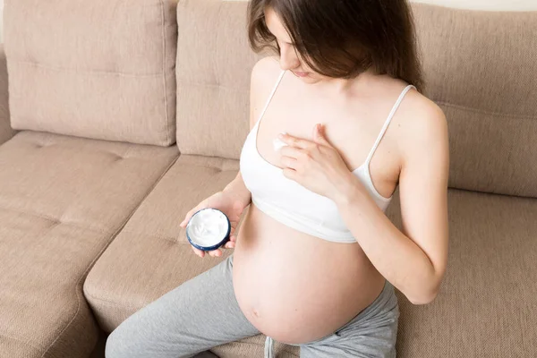 pregnant woman applying stretch mark cream to belly. pregnancy, people and maternity concept. pregnant apply anti-stretch mark cream on her breast.
