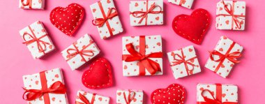 Beyaz hediye kutularının ve renkli arka planda kırmızı tekstil kalplerinin kompozisyonu. Sevgililer Günü konsepti.