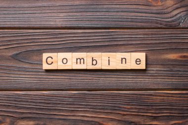 Tahta bloğa yazılmış bir kelime. Ahşap masa üzerindeki COMBINE metin desing, konsept.