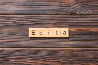 Tahta bloğa yazılmış EBITA kelimesi. EBITA metni çimento masa üzerinde desing, konsept için.