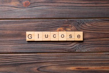 Tahta bloğa yazılmış GLUCOSE kelimesi. Çimento masasındaki GLUCOSE metni desing, konsept için.
