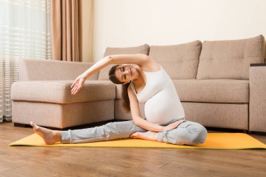 Hamile kadın yoga pozisyonunda otururken meditasyon yapıyor. Coronavirus zamanında hamilelik Yoga ve Spor Konsepti üzerine meditasyon.