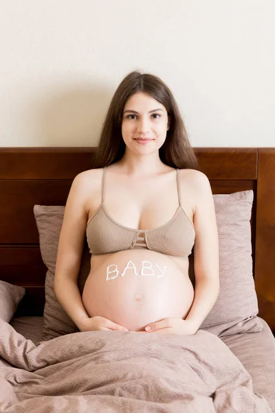 Uma Menina Grávida Senta Casa Cama Mancha Creme Marca Estiramento — Fotografia de Stock