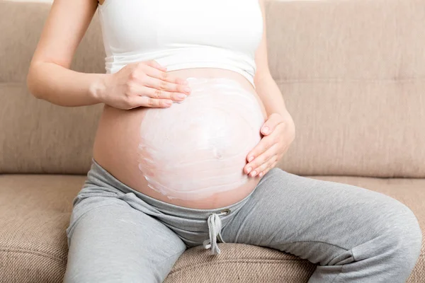 Těhotná Dívka Sedí Doma Posteli Rozmazává Břicho Krém Proti Striím — Stock fotografie