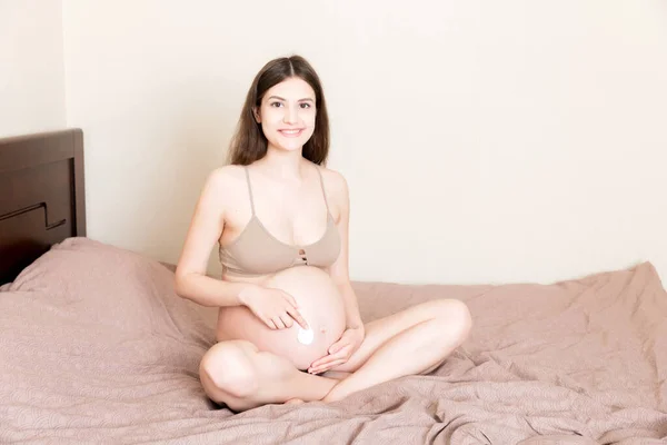 Uma Menina Grávida Senta Casa Cama Mancha Creme Marca Estiramento — Fotografia de Stock