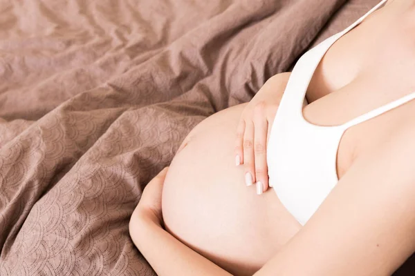 孕妇坐在床上 在家里摸着肚子 预期怀孕概念 — 图库照片