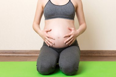 Hamile kadın yoga pozisyonunda otururken meditasyon yapıyor. Coronavirus zamanında hamilelik Yoga ve Spor Konsepti üzerine meditasyon.