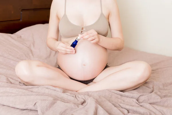 孕妇在腹部涂伸展标记霜 人和生育的概念 孕妇在腹部涂抗张性标记霜 — 图库照片