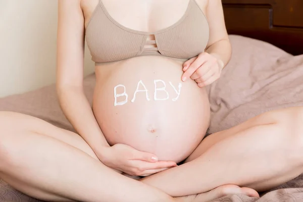 Μια Έγκυος Κάθεται Σπίτι Στο Κρεβάτι Και Πασαλείβει Μια Κρέμα — Φωτογραφία Αρχείου