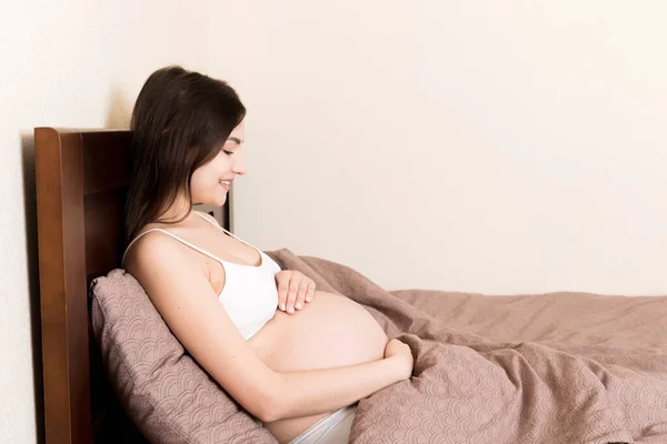 Mujer Embarazada Sentada Cama Tocándose Vientre Casa Concepto Expectativa Embarazo —  Fotos de Stock