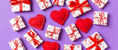 Beyaz hediye kutularının ve renkli arka planda kırmızı tekstil kalplerinin kompozisyonu. Sevgililer Günü konsepti.