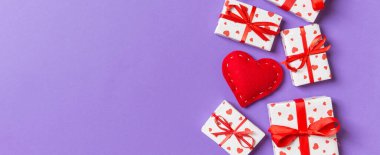 Hediye kutularının ve renkli arka planda kırmızı tekstil kalplerinin üst görüntüsü. Kopya alanı ile Sevgililer Günü konsepti.