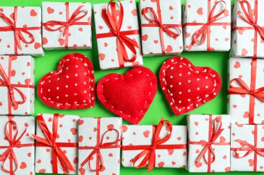 Beyaz hediye kutularının ve renkli arka planda kırmızı tekstil kalplerinin kompozisyonu. Sevgililer Günü konsepti.