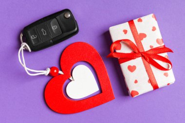 Hediye kutusunun üst görüntüsü, araba anahtarı ve renkli arka planda tahta kalp. Sevgililer Günü için lüks hediye.
