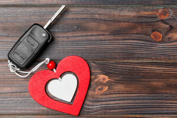 Top view of car key and heart as a present for Valentine's day on wooden background. Romance concept with copy space.