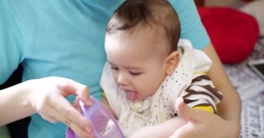 Anne bebeği kollarında tutuyor ve oğlunu kaşıkla besliyor. aile, yemek, çocuk, yeme ve ebeveynlik kavramı