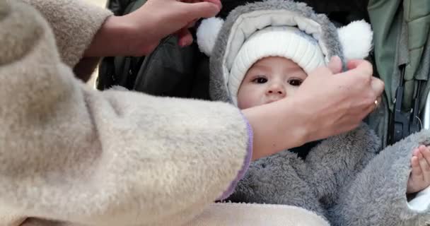 Ung mamma på en sommardag täcker ett nyfött barn med en filt i en barnvagn — Stockvideo