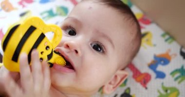 Bebek, çocukluk konsepti. Gülümseyen mutlu bebeğin ip ile oynadığı yakın plan. Diş kesimi. İlk dişler. Neşesiz dişsiz 7 ay bebek ısırığı, kemiren oyuncak