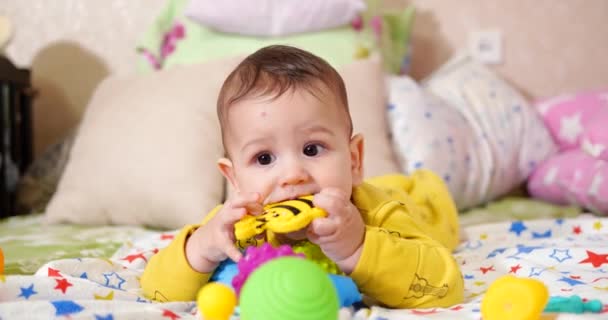 Criança, conceito de infância - close-up de sorrir feliz bebê brinca com um teether. Corte dos dentes. Os primeiros dentes. Joy toothless 7 meses bebê mordida, rói brinquedo teether — Vídeo de Stock