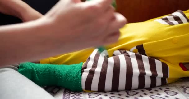 Matka wkłada skarpetki na swoje nowo narodzone stopy dziecka w ome. — Wideo stockowe