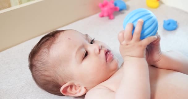 Bebé, concepto de la infancia - primer plano de sonreír feliz Bebé juega con un mordedor. Cortar los dientes. Primeros dientes. Joy mordida de bebé sin dientes de 7 meses, roe el juguete del mordedor — Vídeo de stock